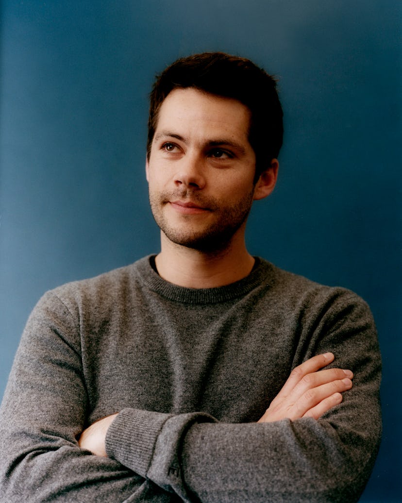 Dylan O’Brien posing in a grey sweater