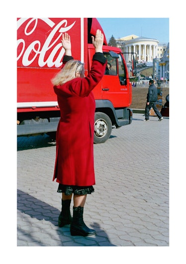 A person waving their passport next to a Coca Cola truck