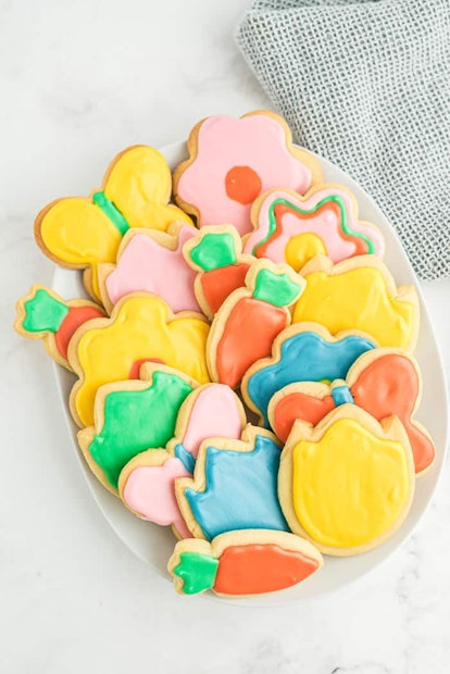 A plate full of sugar cookies iced and decorated for spring