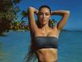 Kim Kardashian wearing SKIMS swimwear two piece bikini with a bandeau top and swim shorts.