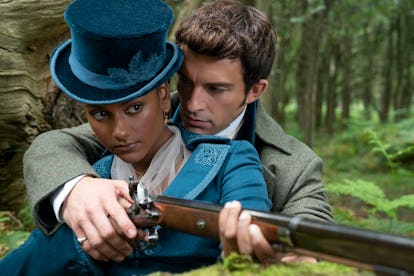 Anthony Bridgerton showing Kate Sharma how to hold a gun in a forest