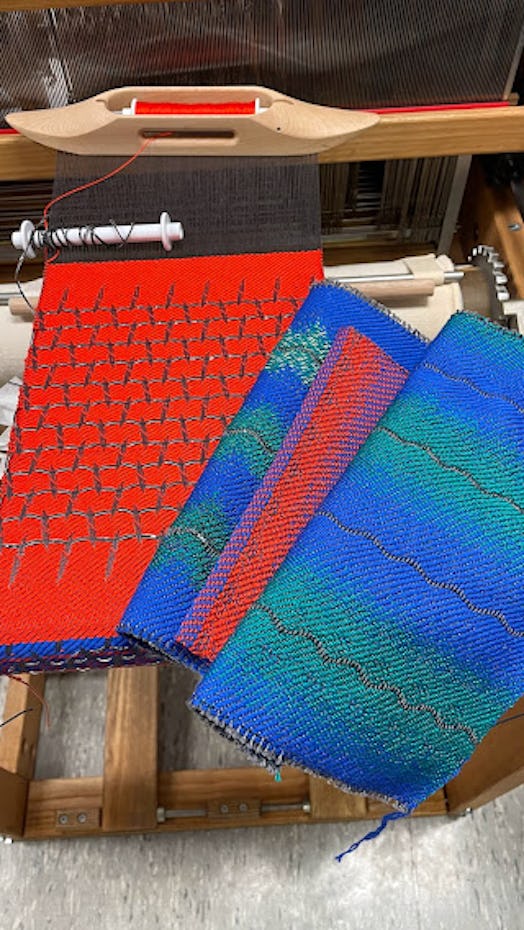 Red, blue, and green textiles on a loom.