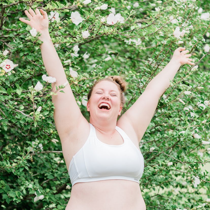 Happy young woman with her arms in the air after reading the spring equinox 2022 horoscope for her z...