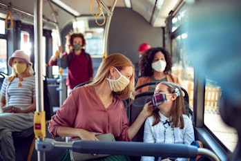 Masked mom and daughter riding a bus