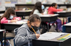 masked student does her work in a second and third grade class.