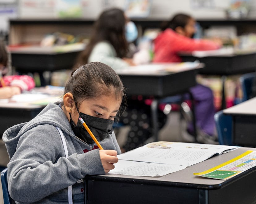 masked student does her work in a second and third grade class.