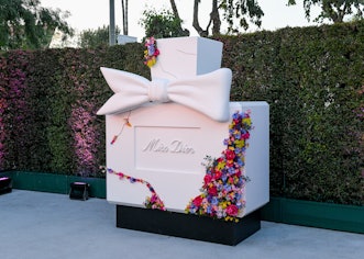 The Miss Dior photo booth containing white oversized bottle of the perfume decorated with flowers.