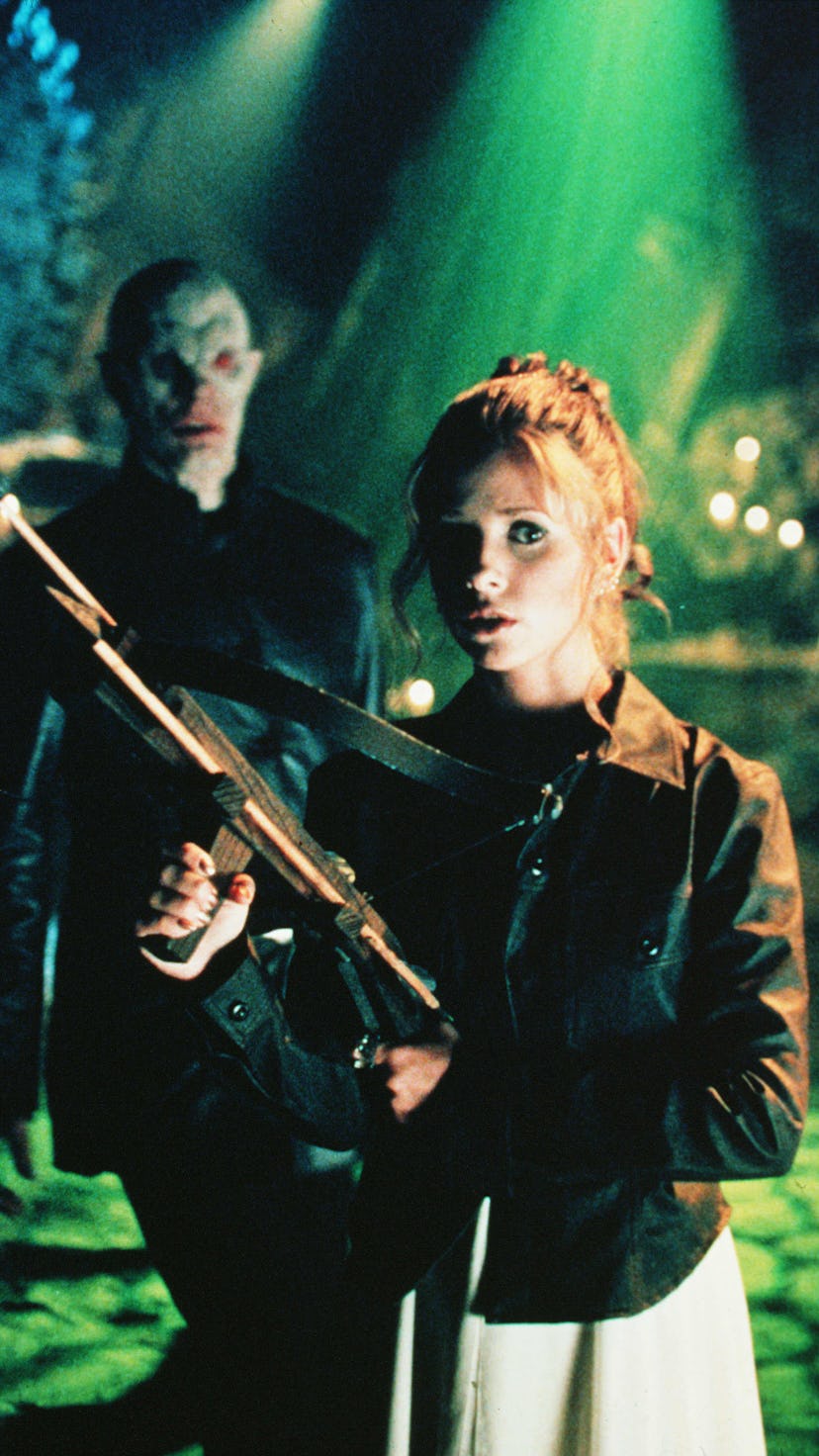 Sarah Michelle Gellar as Buffy The Vampire Slayer holding a crossbow in a scene and a vampire behind...