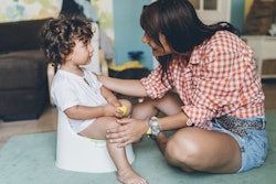 mother encouraging child to use toilet with potty training toys 