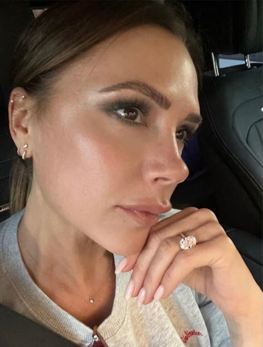 A selfie of Victoria Beckham in the car, looking into the distance with her hand on her chin 