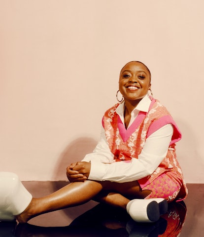 Quinta Brunson sitting and smiling on the floor in PH5 sweater and skirt, DKNY top and white Simon M...