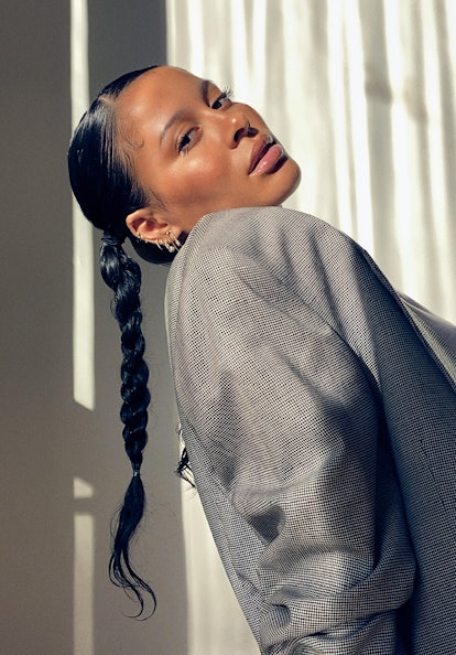 A portrait of sun-kissed Sami Miró in a grey blazer with a long braid looking over her right shoulde...