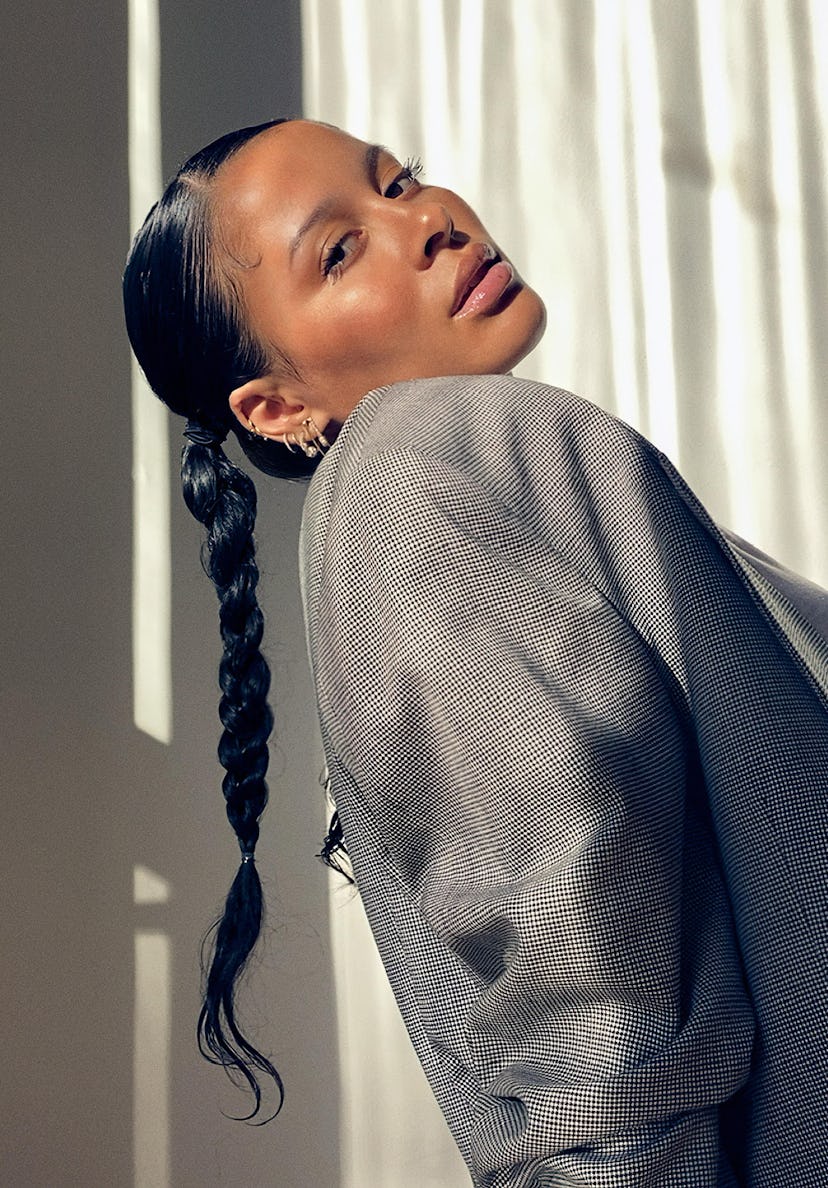 A portrait of sun-kissed Sami Miró in a grey blazer with a long braid looking over her right shoulde...
