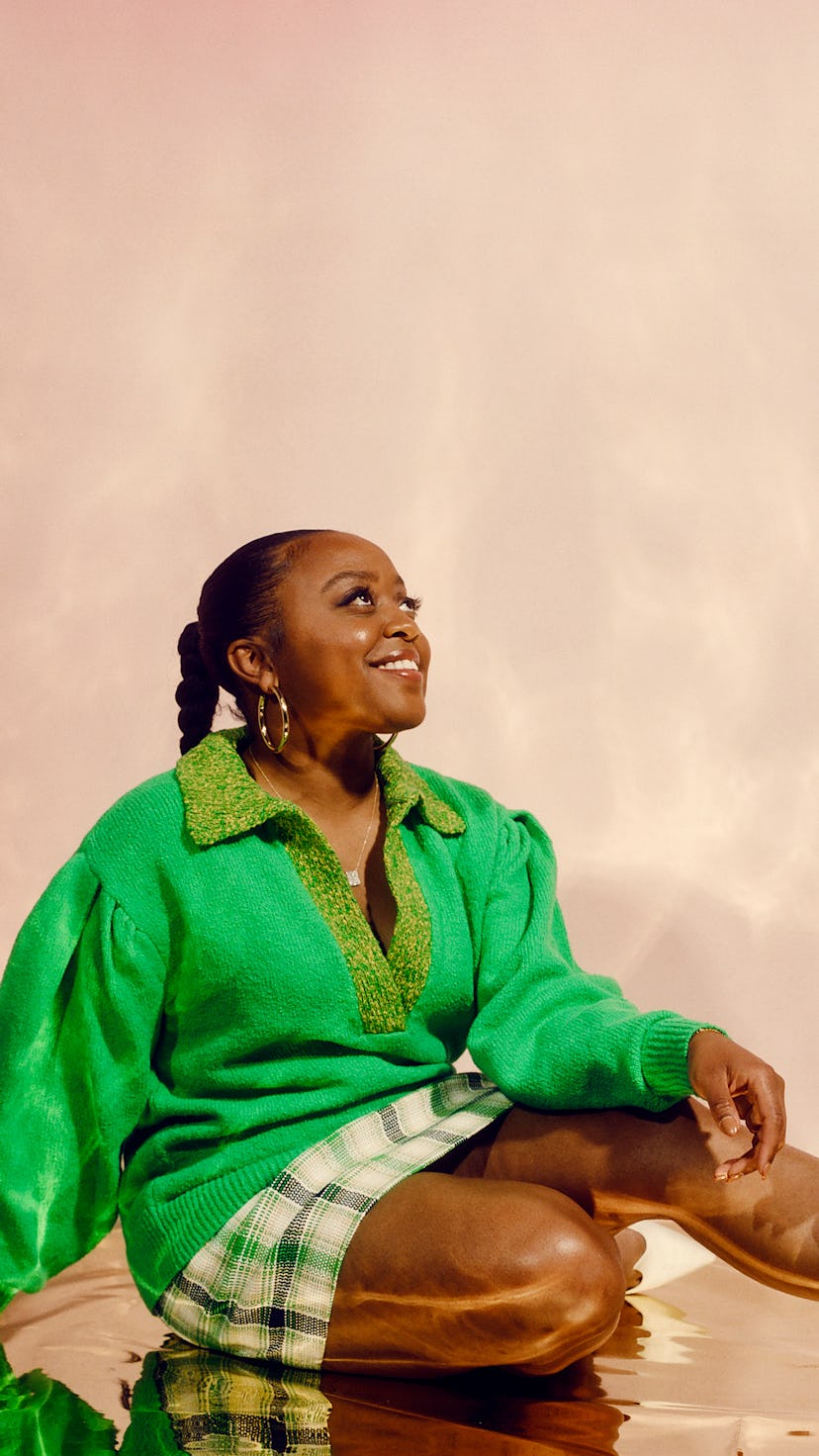 Quinta Brunson sitting and smiling on the floor