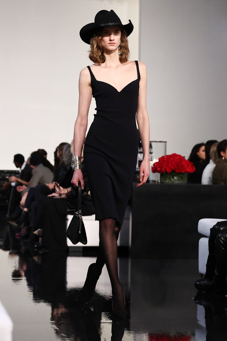 Model on the NY Fashion Week Fall 2022 runway in a Ralph Lauren black dress, black cowboy hat, carry...