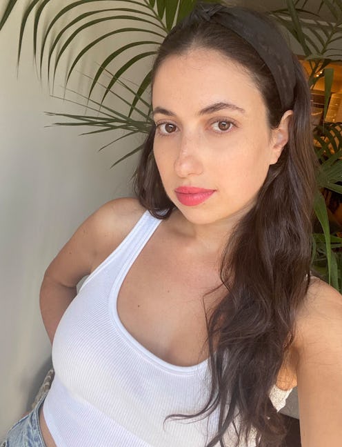 Rebecca Iloulian in a white tank top wearing spring lipstick shade while posing