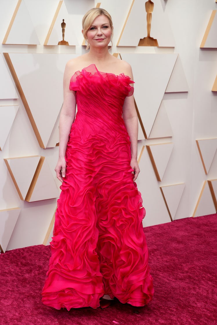 Kristen Dunst on the red carpet in a red open-shoulder Christian Lacroix dress at the 2022 Oscars