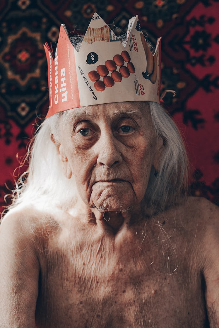 An elderly woman wears a crown.