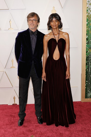 Liya Kebede wearing a burgundy Alaia dress while standing next to Philippe Rousselet at the 2022 Osc...