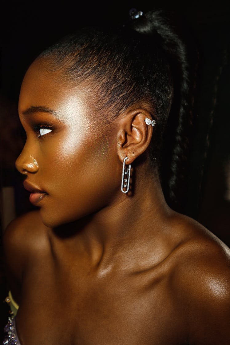 A side-profile of Demi Singleton with her long braid and, an earring and a small ear cuff 