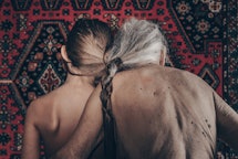 A young girl and her grandmother, from the back, neither wear shirts.
