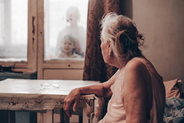 An elderly woman looks out an opaque window. From 