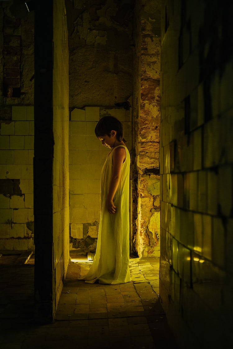A child in a white nightdress stands in the light.