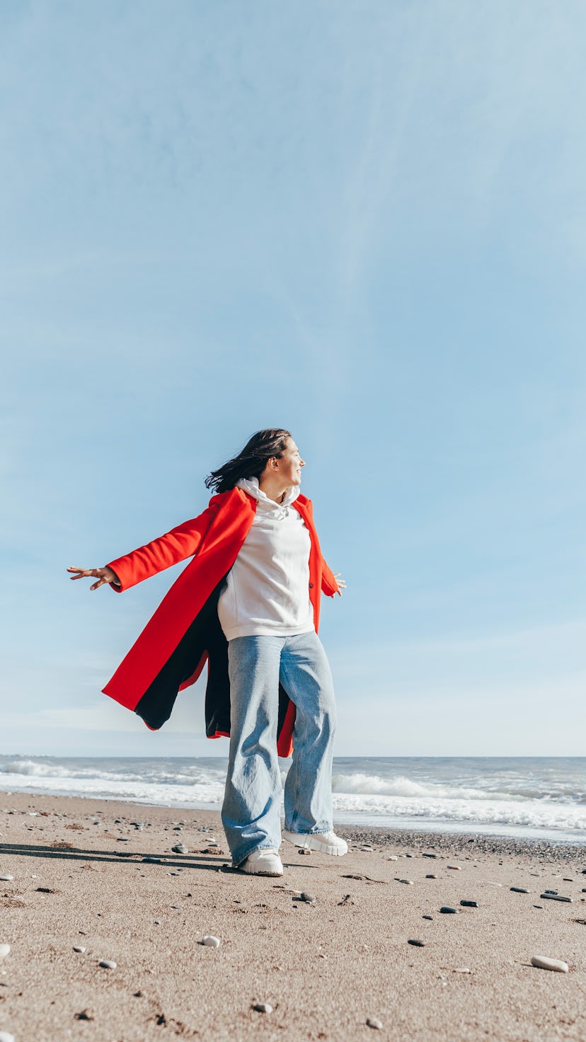 Young woman walking on the beach ahead of the April 2022 new moon in Aries, which will affect every ...
