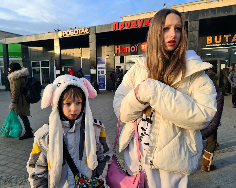 A teenage girl and a little boy with luggage at a train station in Ukraine