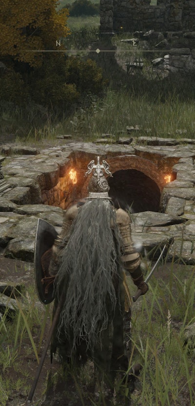 screenshot from Elden Ring of the main character getting ready to go into a cave in the ground