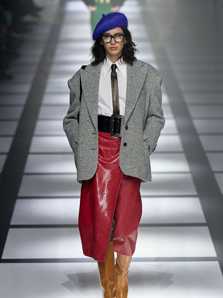 A model in gucci's blue beret red skirt and grey jacket