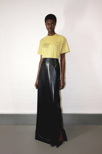 a model wearing a yellow Kwaidan Editions t shirt and black long maxi skirt