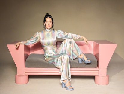 Katy Perry sitting on a pastel pink couch wearing KPC shoes