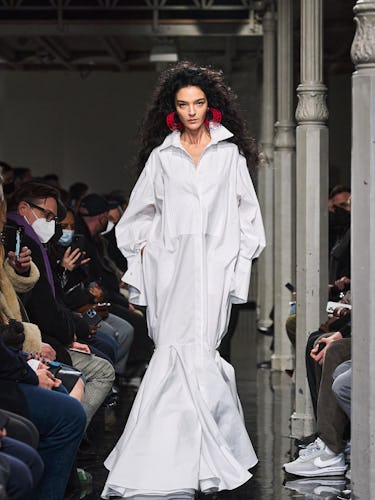 Model wearing white azzedine alaia dress with collar and red earrings