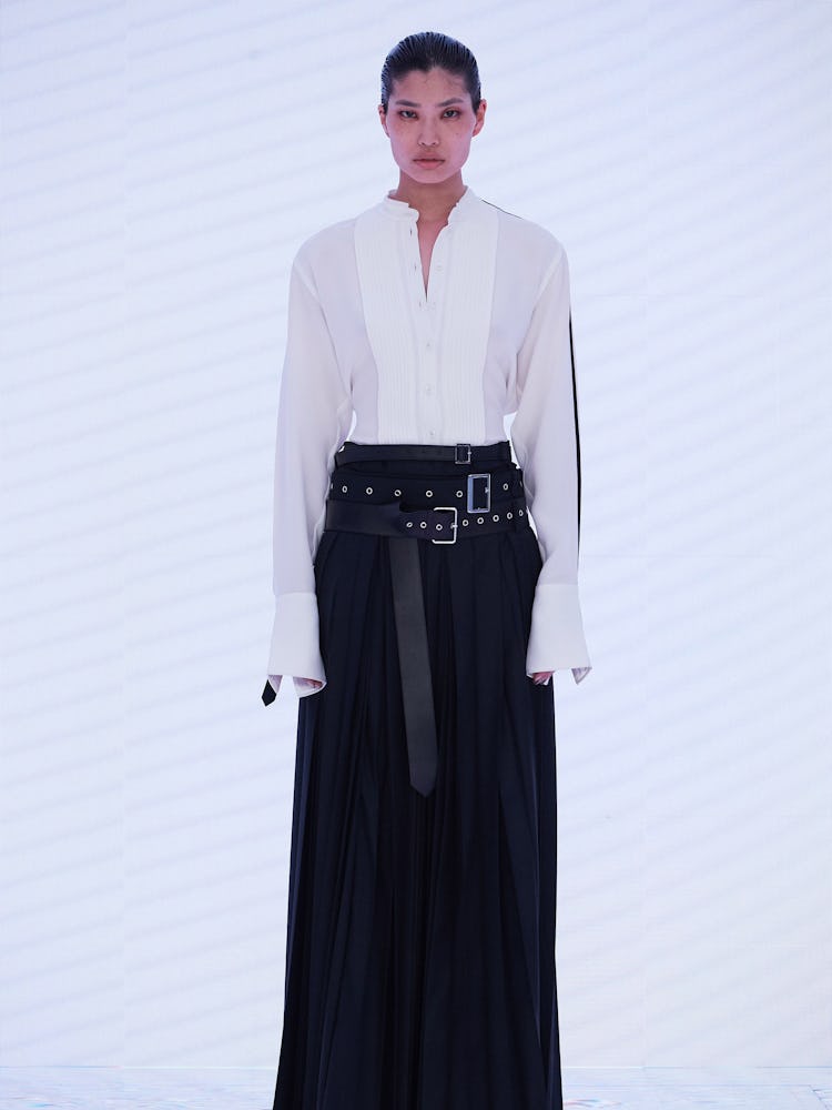 A model wearing a white shirt and black long Peter Do skirt