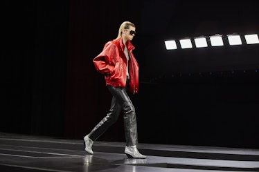 A model walking the runway at Men's Fashion Week Fall 2022 in a red jacket and black pants