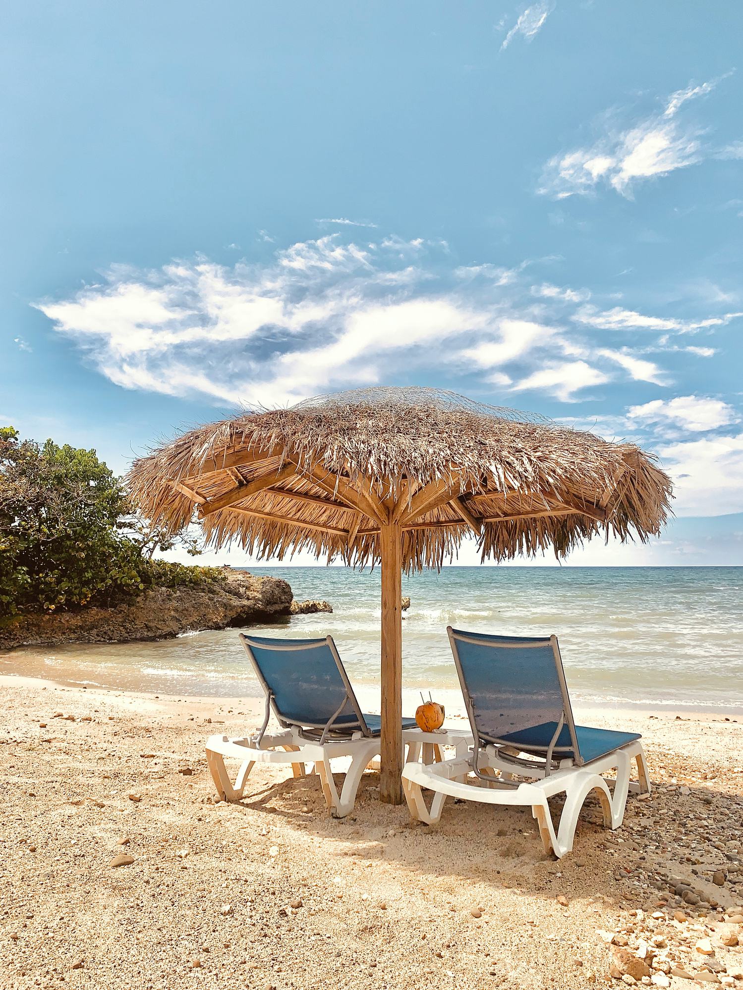 Two chairs on a beach under umbrella 