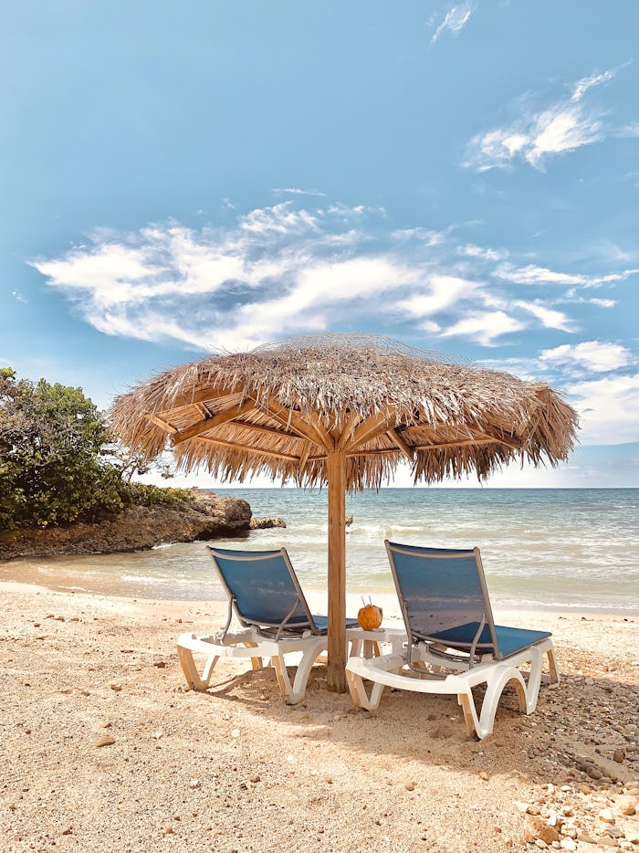 Two chairs on a beach under umbrella