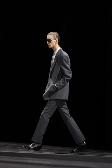 A model walking in a black Celine suit at the Men’s Fashion Week Fall 2022