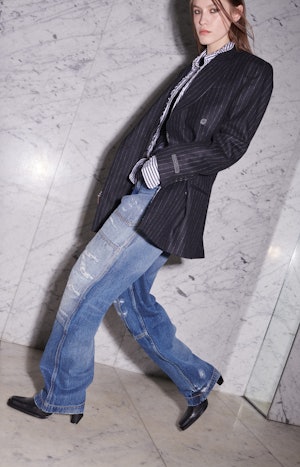 a model wearing slouchy jeans and an oversize pinstripe blazer by EYTYS