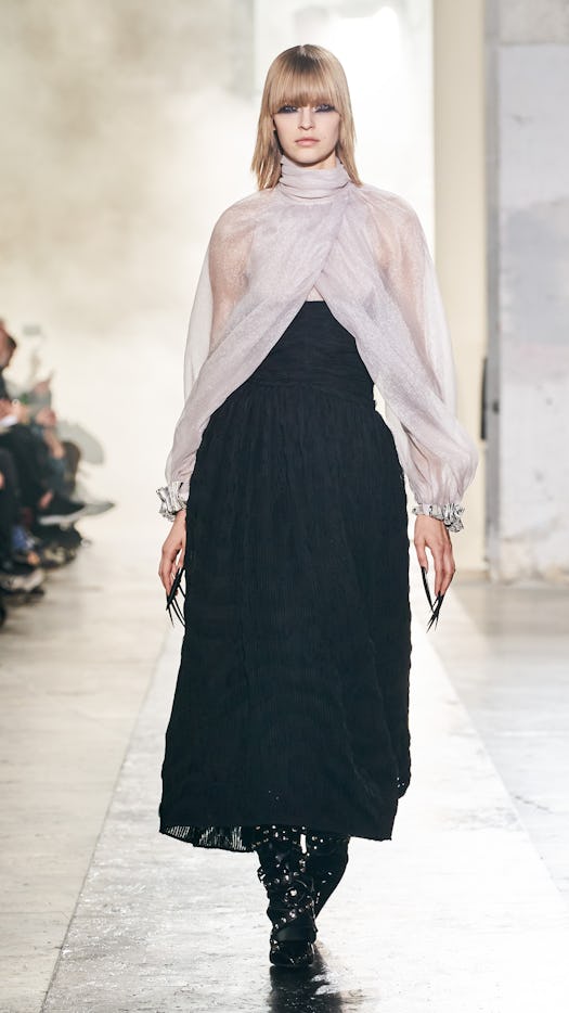 a model wearing a sheer blouse and black skirt on the Rochas runway