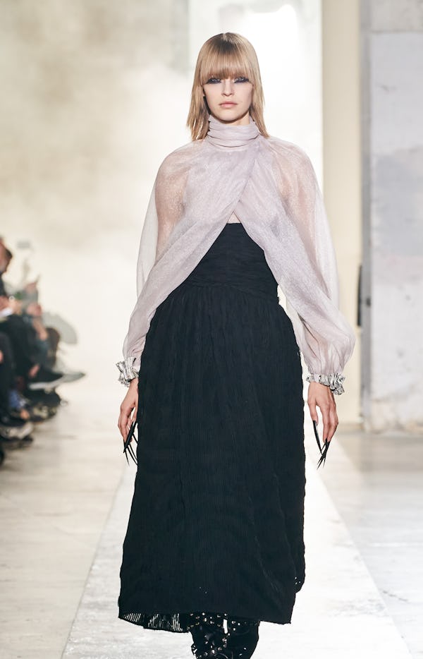 a model wearing a sheer blouse and black skirt on the Rochas runway