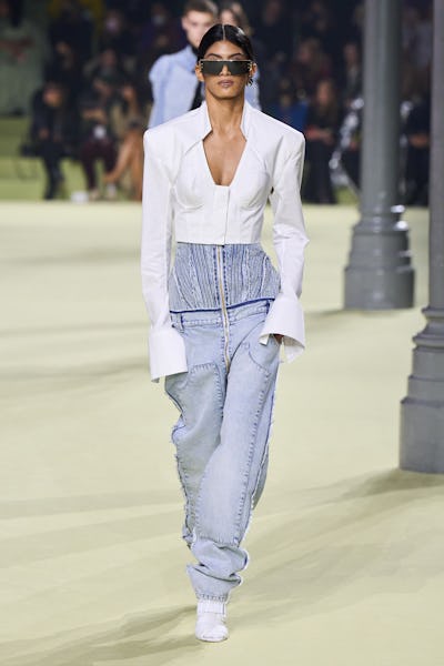 a model wearing a white corseted jacket and slouchy jeans on the Balmain runway