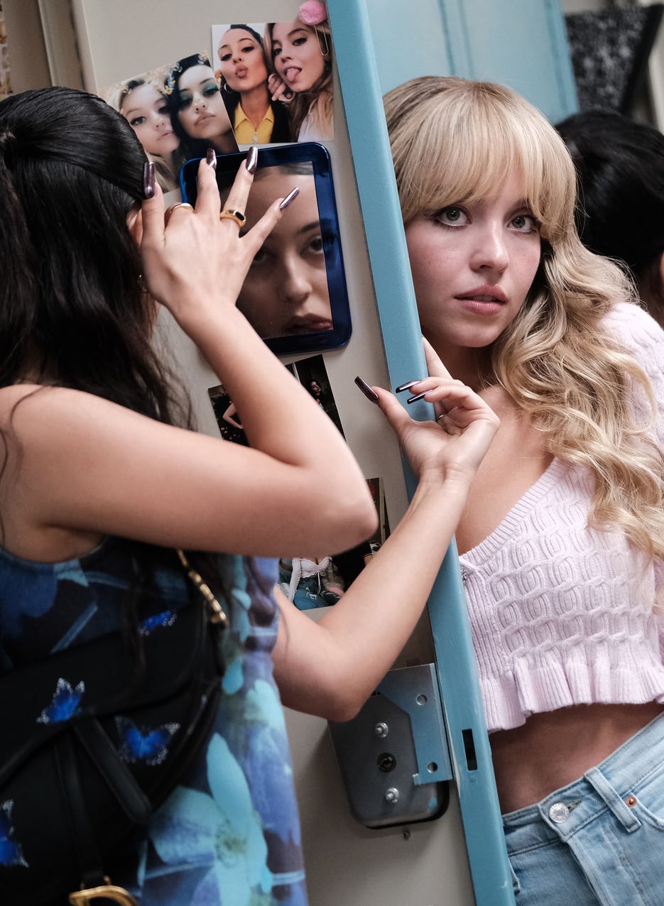 Maddy (Alexa Demie) looking in a mirror and Cassie (Sydney Sweeney) next to her locker, showing off ...
