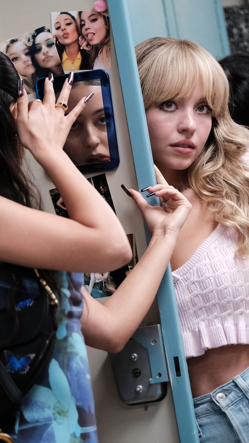 Maddy (Alexa Demie) looking in a mirror and Cassie (Sydney Sweeney) next to her locker, showing off ...