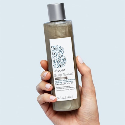 A hand holding Briogeo's new Scalp Revival Charcoal Shampoo for anti-dandruff.