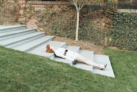 A lifelike doll of a redhead woman lying on the stairs in a park