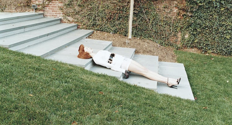 A lifelike doll of a redhead woman lying on the stairs in a park