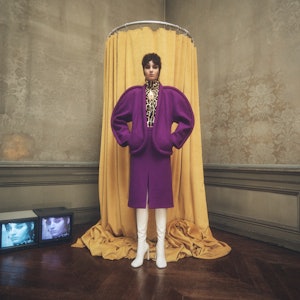 a model wearing a purple curved suit jacket and skirt by Dries Van Noten