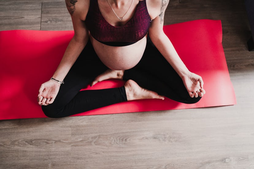 pregnant woman sitting on a yoga mat 